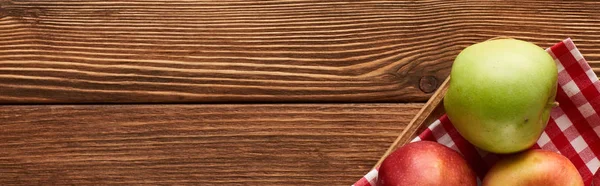 Панорамный снимок клетчатой скатерти с яблоками на деревянной поверхности с копировальным пространством — стоковое фото