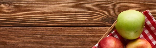 Panoramic shot of checkered tablecloth with apples on wooden surface with copy space — Stock Photo