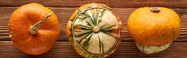 Panoramic shot of ripe pumpkins on brown wooden surface — Stock Photo