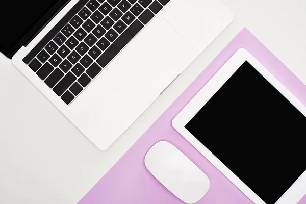 Flat lay com laptop, tablet digital com tela em branco e mouse no fundo violeta e branco — Fotografia de Stock