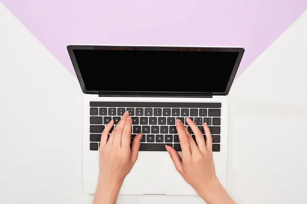 Cropped view of woman using laptop on violet and white background — Stock Photo