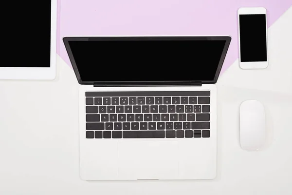 Pose plate avec ordinateur portable, tablette numérique, smartphone avec écran blanc et souris d'ordinateur sur fond violet et blanc — Photo de stock