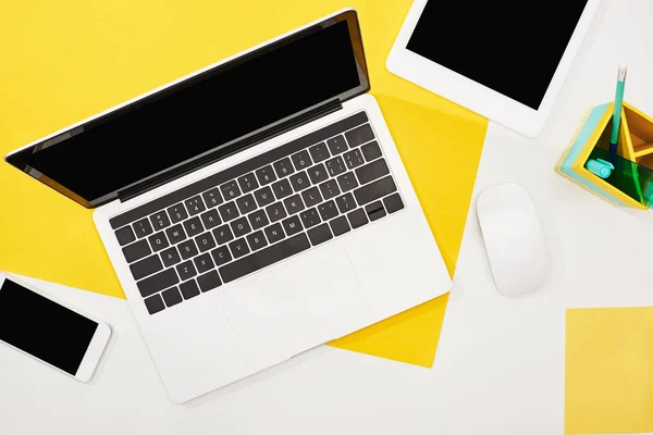 Vue du haut de l'ordinateur portable, tablette numérique, smartphone avec écran blanc et souris d'ordinateur sur fond jaune et blanc — Photo de stock