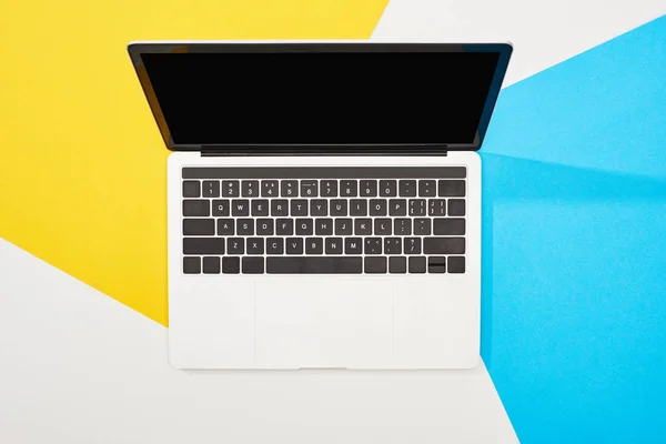 Вид зверху ноутбука з порожнім екраном на жовтому, синьому та білому тлі — стокове фото