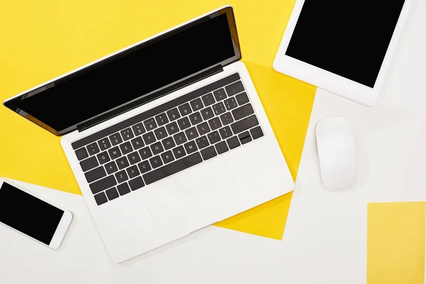 Vista dall'alto di laptop, smartphone, tablet digitale con schermo bianco e mouse del computer su sfondo giallo e bianco — Foto stock
