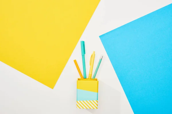 Vista superior de materiais de escritório coloridos no fundo amarelo, azul e branco — Fotografia de Stock