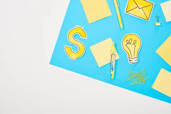 Vue du dessus du lieu de travail avec fournitures de bureau jaunes, icônes en papier sur fond bleu et blanc — Photo de stock