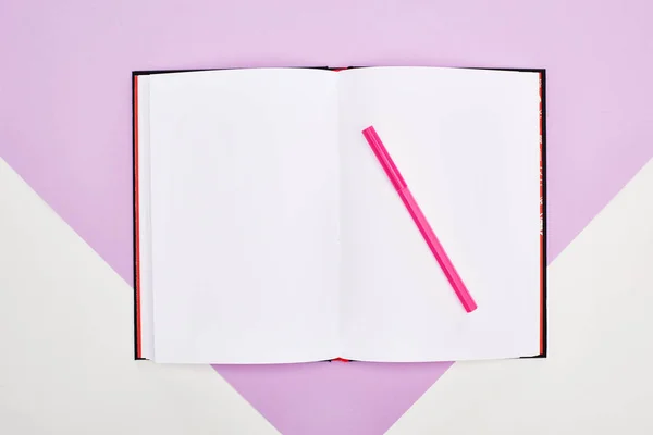 Top view of open empty notebook with felt pen on violet and white background — Stock Photo