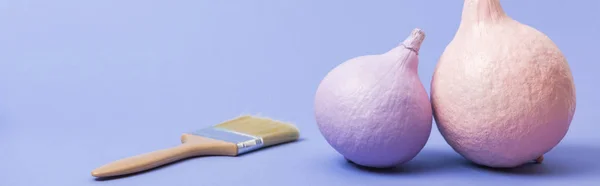 Panoramic shot of painted pink and violet pumpkins with paintbrush on violet background — Stock Photo