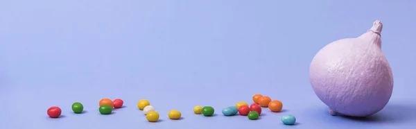 Панорамний знімок розфарбованого фіолетового гарбуза з цукерками на фіолетовому фоні — стокове фото