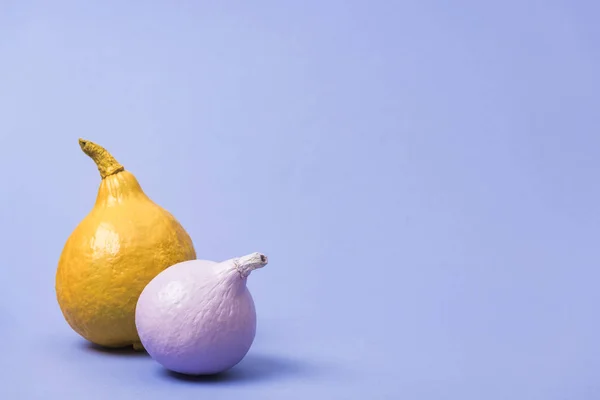 Bemalte gelbe und violette Kürbisse auf violettem Hintergrund — Stockfoto