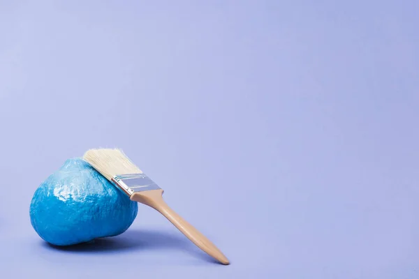 Festive painted blue pumpkin with paintbrush on violet background — Stock Photo