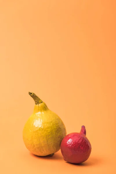 Пофарбовані червоні та жовті гарбузи на помаранчевому барвистому фоні — стокове фото
