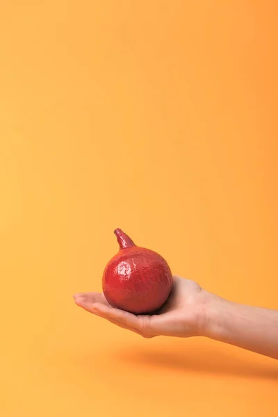 Cropped view of woman holding red painted pumpkin on orange colorful background — Stock Photo