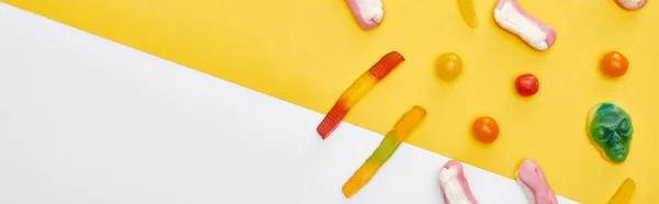 Plan panoramique de bonbons gommeux colorés sur fond jaune et blanc, festin d'Halloween — Photo de stock