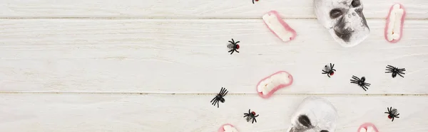 Vista superior de dentes de goma, crânios e aranhas na mesa de madeira branca, deleite de Halloween — Fotografia de Stock