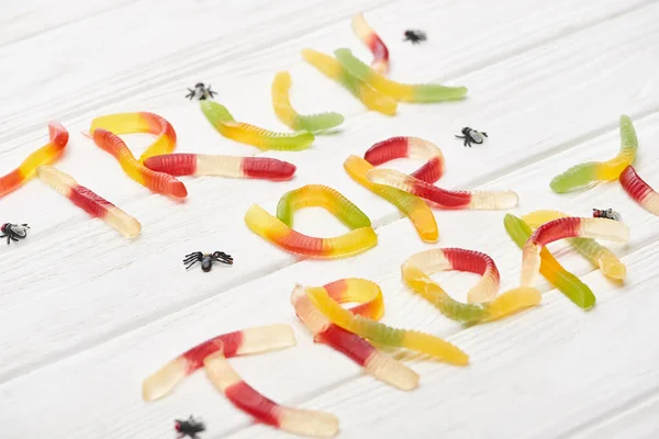 Truque ou tratar letras feitas de doces de goma coloridos na mesa de madeira branca com aranhas, deleite de Halloween — Fotografia de Stock