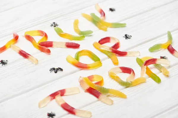 Trick-oder Leckerli-Schriftzug aus bunten Gummibonbons auf weißem Holztisch mit Spinnen, Halloween-Leckerbissen — Stockfoto