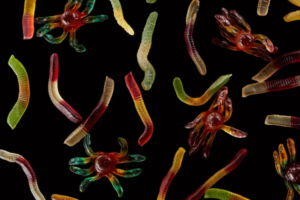 Top view of colorful gummy spiders and worms isolated on black, Halloween treat — Stock Photo