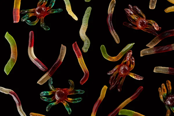 Vue de dessus des araignées et vers gommeux colorés isolés sur noir, Halloween traiter — Photo de stock