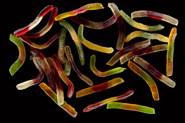 Вид зверху барвисті жувальні черви ізольовані на чорному, Хеллоуїн лікувати — стокове фото