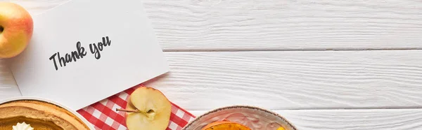 Vista superior da torta de abóbora com cartão de agradecimento na mesa branca de madeira com maçãs, tiro panorâmico — Fotografia de Stock