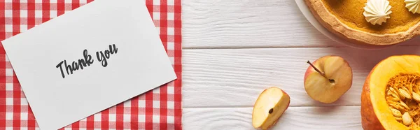Вид сверху на тыквенный пирог с благодарственной открыткой на деревянном белом столе с яблоками, панорамный снимок — стоковое фото