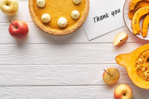 Draufsicht auf köstlichen Kürbiskuchen mit Dankeskarte auf weißem Holztisch mit Äpfeln — Stockfoto