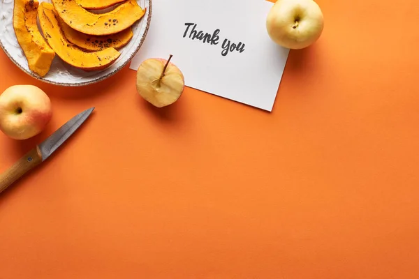 Top view of pumpkin, apples, knife and thank you card on orange background — Stock Photo