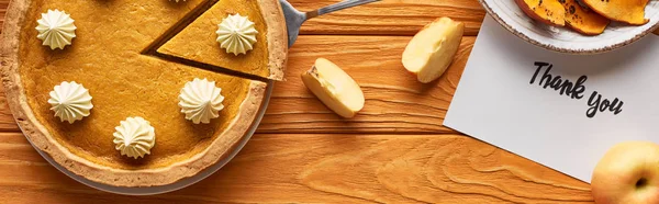 Вид сверху на тыквенный пирог с благодарственной открыткой на деревянном столе с яблоками, панорамный снимок — стоковое фото
