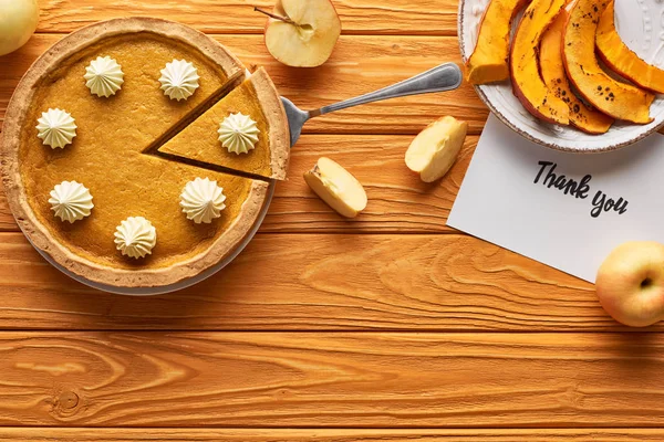 Top view of pumpkin pie with thank you card on wooden table with apples — Stock Photo