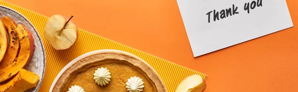Panoramic shot of delicious pumpkin pie with thank you card on orange background with apples — Stock Photo