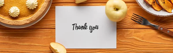 Top view of delicious pumpkin pie, apples and thank you card on wooden orange table, panoramic shot — Stock Photo