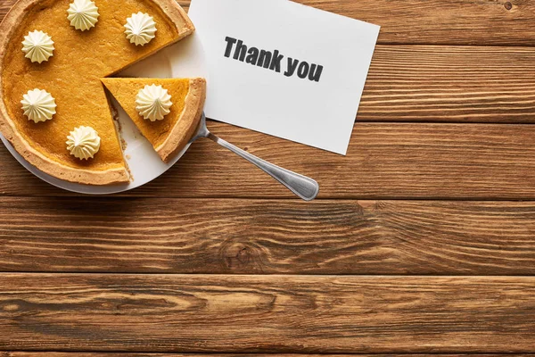 Vista dall'alto di gustosa torta di zucca e biglietto di ringraziamento su tavolo rustico in legno — Foto stock