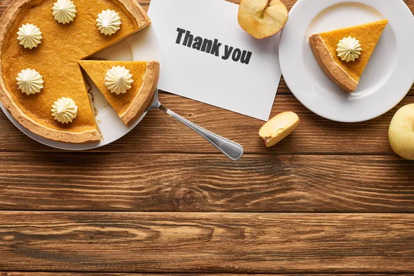 Vista dall'alto di torta di zucca saporita, mele e biglietto di ringraziamento su tavolo rustico di legno — Foto stock