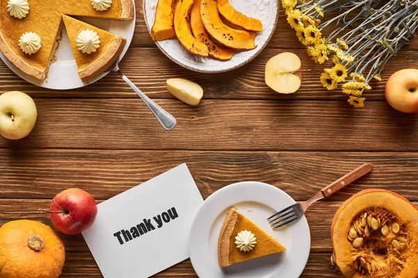 Vista superior da torta de abóbora saborosa, flores, maçãs e cartão de agradecimento na mesa rústica de madeira — Fotografia de Stock
