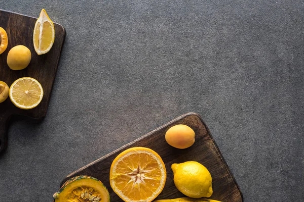 Vista superior de frutas y verduras amarillas en tablas de cortar de madera sobre fondo texturizado gris con espacio para copiar - foto de stock