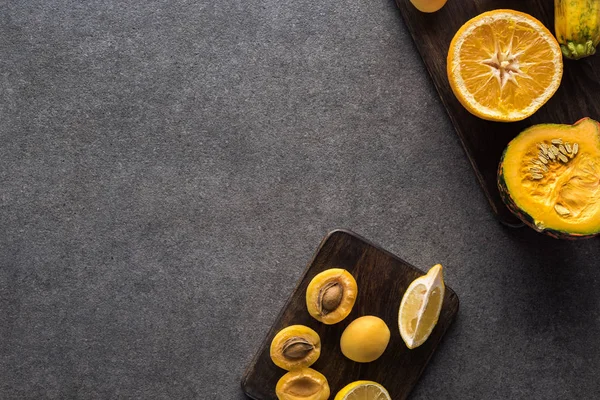 Вид сверху на желтые фрукты и овощи на деревянных досках на сером текстурированном фоне с копировальным пространством — стоковое фото