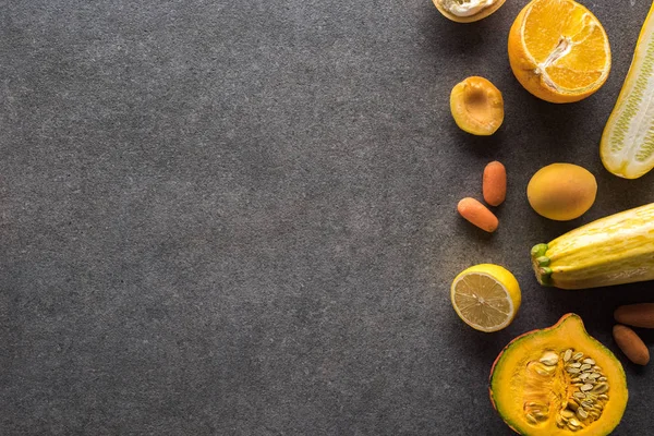 Vista superior de frutas y verduras amarillas sobre fondo texturizado gris con espacio para copiar - foto de stock