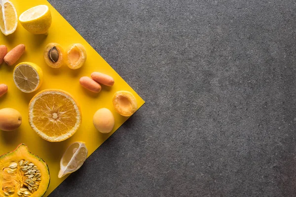 Вид сверху на фрукты и овощи на желтом и сером фоне — стоковое фото