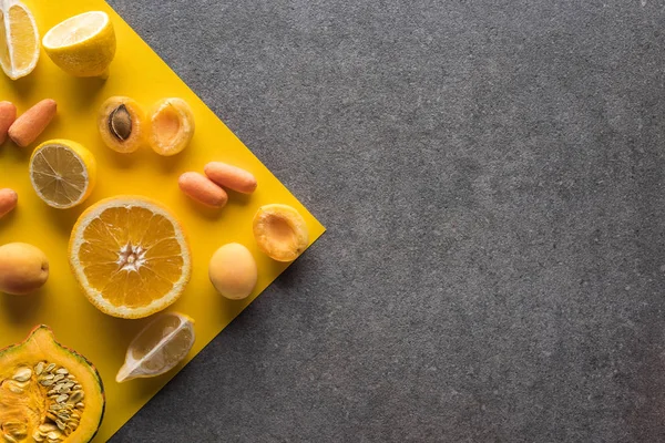 Вид зверху на фрукти та овочі на жовтому та сірому фоні — стокове фото