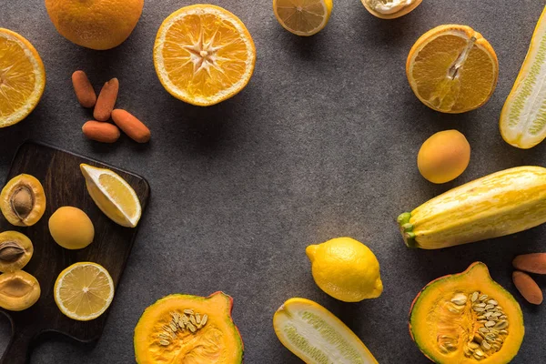 Draufsicht auf gelbes Obst und Gemüse und hölzerne Schneidebretter auf grauem Hintergrund — Stockfoto