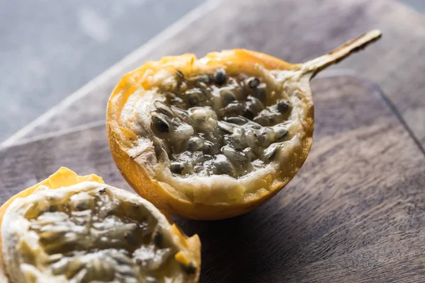 Vista de perto de granadilla doce em tábuas de corte de madeira em fundo cinza — Fotografia de Stock