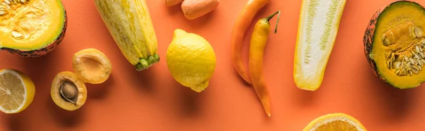 Top view of yellow fruits and vegetables on orange background, panoramic shot — Stock Photo