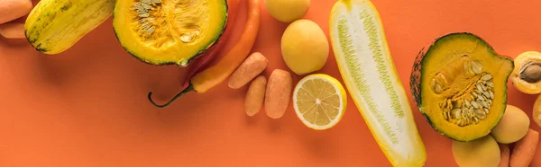 Top view of yellow fruits and vegetables on orange background, panoramic shot — Stock Photo