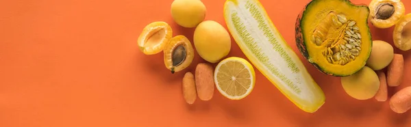 Blick von oben auf gelbes Obst und Gemüse auf orangefarbenem Hintergrund, Panoramaaufnahme — Stockfoto