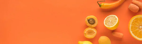 Top view of yellow fruits and vegetables on orange background with copy space, panoramic shot — Stock Photo