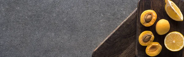 Vista superior de damascos amarelos e limão em tábuas de corte de madeira em fundo texturizado cinza, tiro panorâmico — Fotografia de Stock