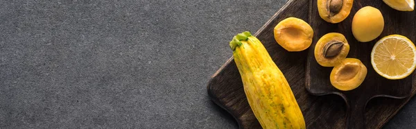 Ansicht von gelbem Obst und Gemüse auf hölzernen Schneidebrettern auf grauem strukturiertem Hintergrund, Panoramaaufnahme — Stockfoto