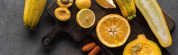Vista superior de frutas e legumes amarelos em tábuas de corte de madeira em fundo cinza texturizado, tiro panorâmico — Fotografia de Stock